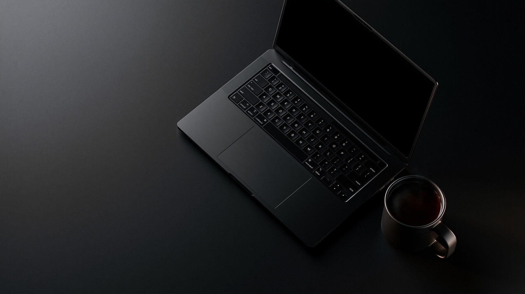 Minimalist black workspace with a laptop and coffee